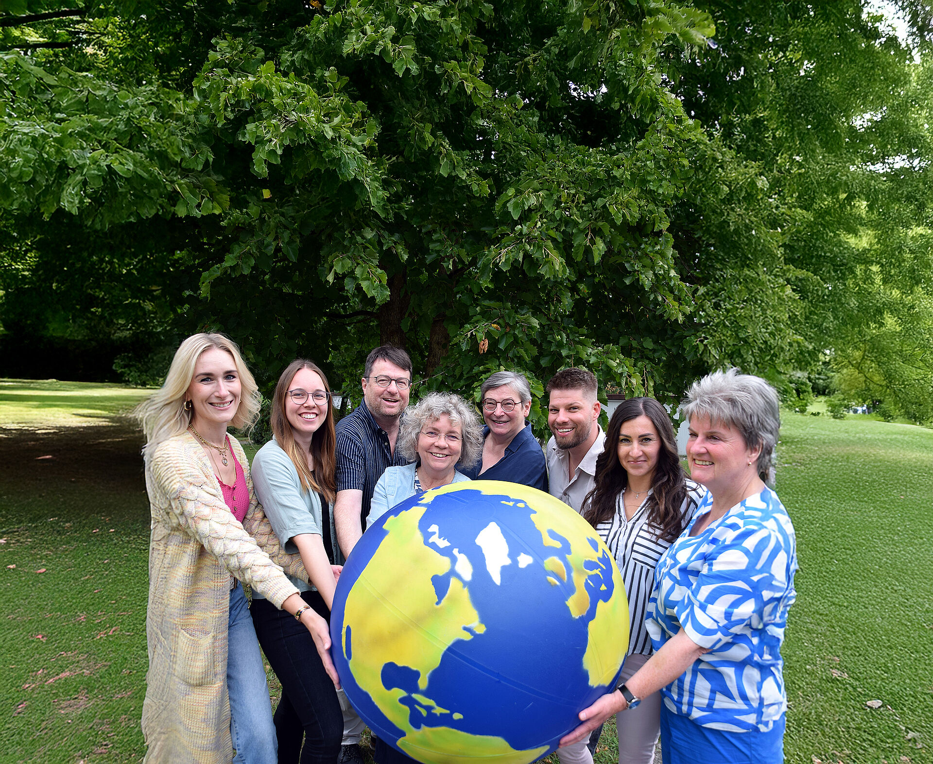 Das Team der Fachstelle eine Welt hält eine große Weltkugel in den Händen